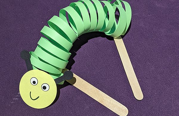 A spiraled green and yellow paper caterpillar puppet. 